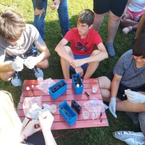 Students gather around water test kits, using chemicals and tablets to test the water.
